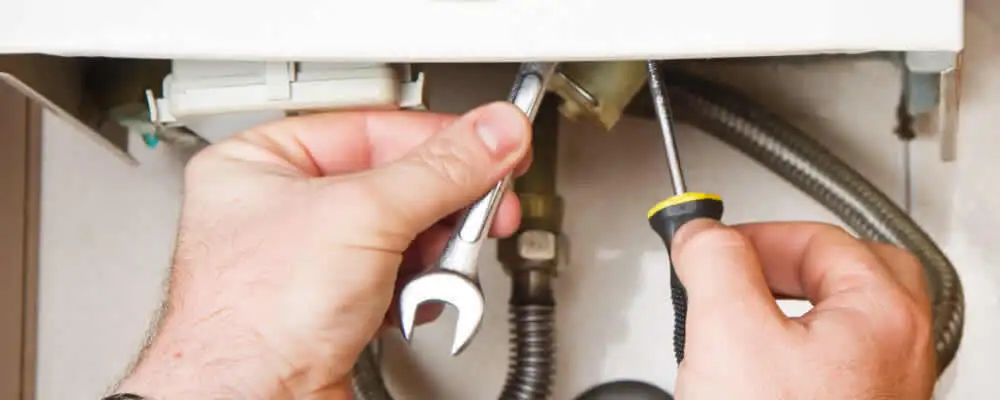 Boiler repair technician tightening pipe fittings and connections in Plymouth, MA