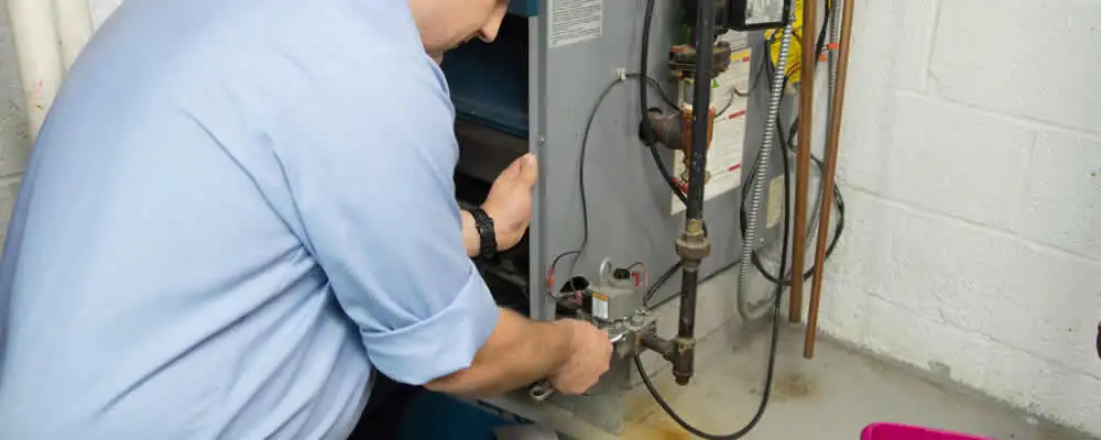 Furnace repair technician inspecting and servicing a home heating system in Plymouth, MA
