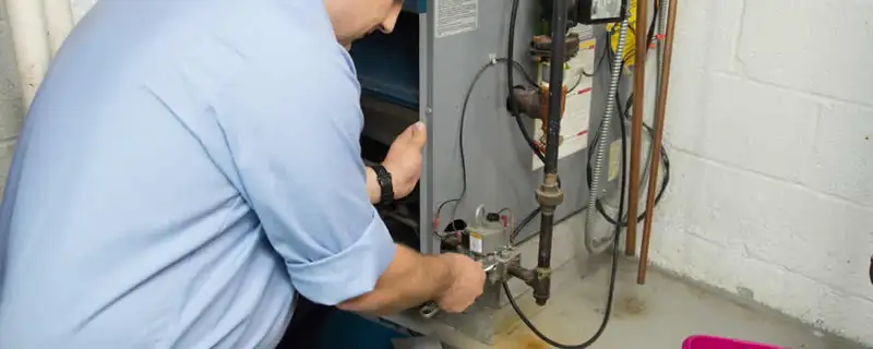 Furnace repair technician inspecting and servicing a home heating system in Plymouth, MA