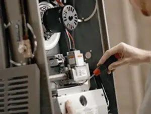 Furnace repair technician inspecting internal components and wiring in Plymouth, MA
