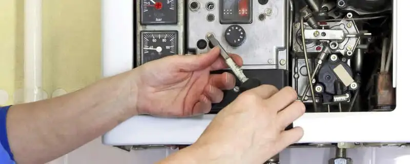 Heating repair technician adjusting boiler controls and components in Plymouth, MA