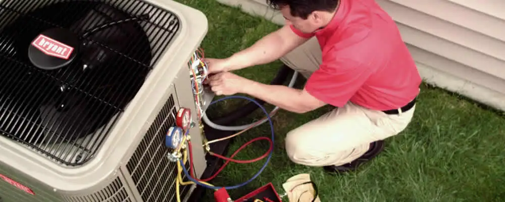 HVAC technician servicing an outdoor air conditioner unit in Plymouth, MA