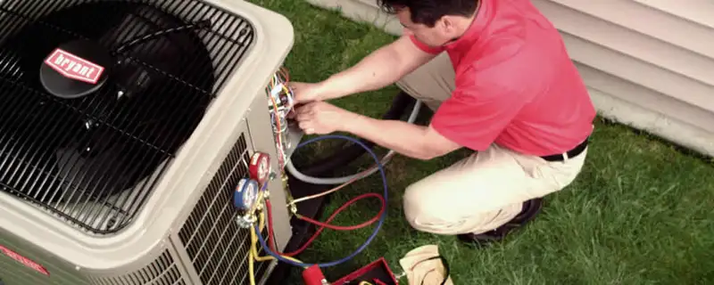 HVAC technician servicing an outdoor air conditioner unit in Plymouth, MA