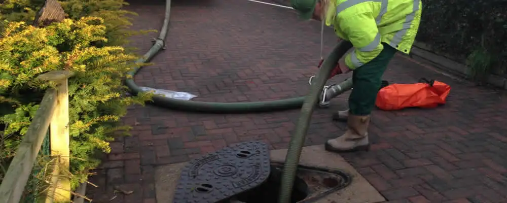 Septic tank cleaning technician servicing a septic tank with a vacuum hose in Plymouth, MA