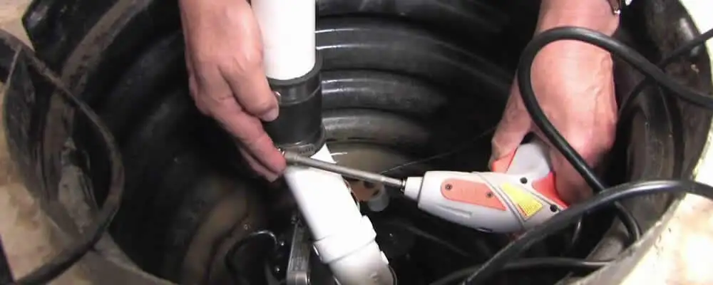 Sump pump installation technician connecting PVC discharge piping in Plymouth, MA