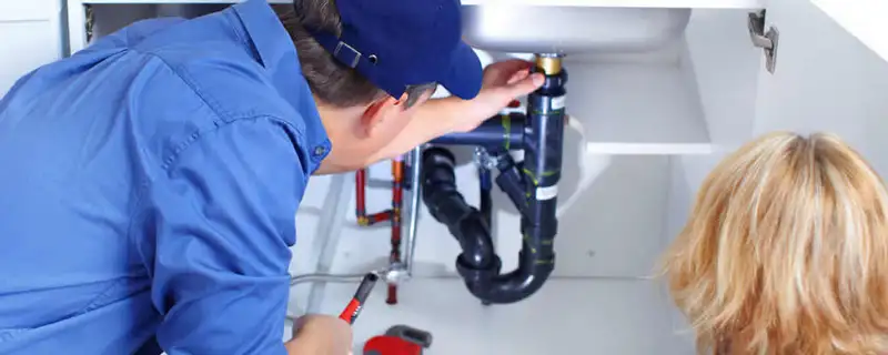 Plumber repairing under-sink drain pipes and fittings in Plymouth, MA
