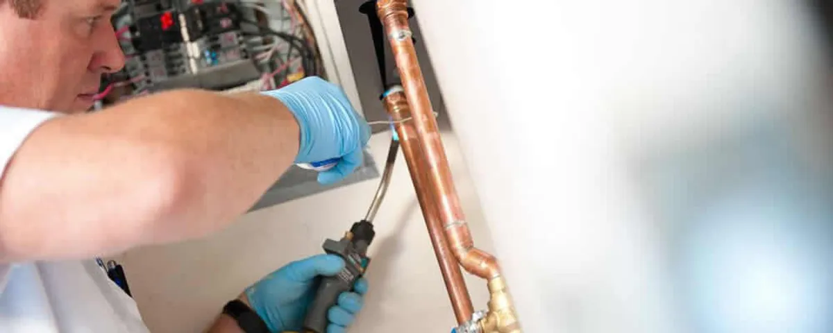 Water heater repair technician testing copper pipe connections and controls in Plymouth, MA